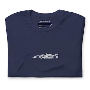 Puede incluir: Camiseta azul marino con un contorno blanco de un coche de carreras. La camiseta tiene cuello redondo y mangas cortas. La etiqueta dice "SPECLINES", "Made in Nicaragua" y "100% combed ring".