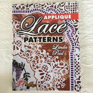 May include: A book titled "Appliqué Lace Patterns" by Linda Pool. The cover features a white lace design on a brown background with purple accents.