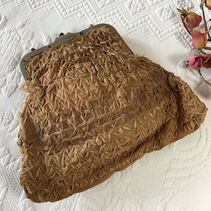 May include: A vintage brown fabric purse with a silver clasp. The purse is decorated with a stitched pattern.