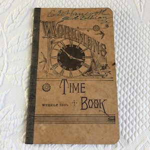 Pode incluir: Um "Workmen's Time Book" vintage com uma capa castanha. A capa apresenta uma ilustração de relógio e as palavras "Workmen's Time Book" em letras decorativas. O texto "Weekly 589 1/2" também é visível. O livro é encadernado com uma lombada escura.