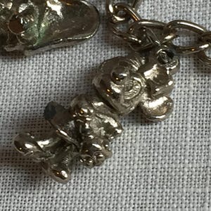 Może przedstawiać: Zbliżenie srebrnego naszyjnika z zawieszkami z łańcuszkiem i trzema szczeg&oacute;łowymi zawieszkami. Zawieszki mają teksturowany, organiczny design. Tło to jasna, teksturowana tkanina.