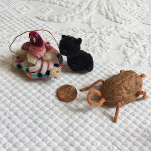 May include: Three small handmade toys: a colorful bird with a long tail, a black cat, and a brown nut with orange pipe cleaner legs.