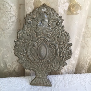 May include: A silver-toned metal tree-shaped wall decor with intricate details and a crystal prism hanging from the top.