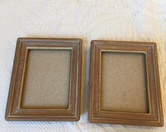 May include: Two rectangular wooden picture frames with a light brown finish and a lighter, distressed effect on the edges. The frames have a simple, classic design and are empty, ready for photos or artwork.