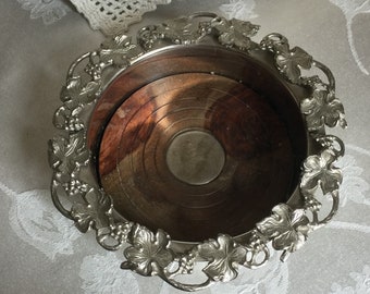 May include: Silver wine bottle holder with a grapevine design and a wooden base.
