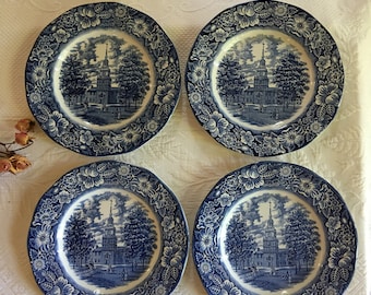 Puede incluir: Juego de cuatro platos de cena de cerámica azul y blanca con borde floral y una imagen central de un edificio con un campanario.
