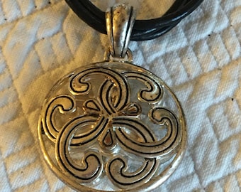 Collier pendentif contemporain vintage de Brighton. Pendentif circulaire tourbillonnant en argent sur trois cordons noirs. Pendentif réversible.