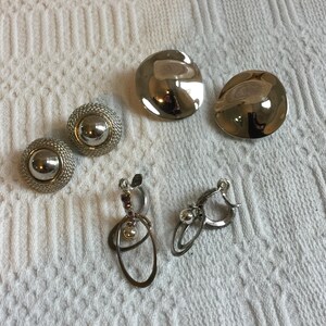 Tre paia di orecchini a clip vintage color argento. Design asimmetrico rotondo a cupola, con cupola rotonda e contorno in corda, e pallina con anelli ovali.