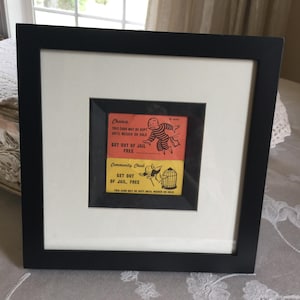 Vintage zwarte vierkante lijst met twee Monopoly-kaarten zonder gevangenis. Wit passe-partout en in het midden kleiner zwart frame in schaduwboxstijl in het midden.