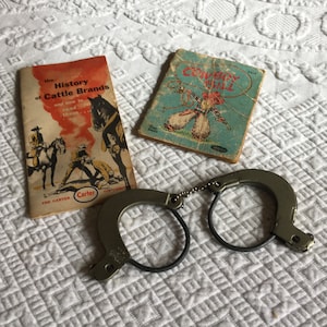 Vintage Toy Cowboy Handcuffs Century 20 Handcuffs. Plus, History of Cattle Brands Carter Oil Co. & Cowboy Bill Book Tiny Tales by Whitman.