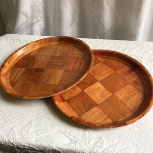 Puede incluir: Dos bandejas redondas de madera con un patrón tejido. Las bandejas son de madera marrón claro y tienen un acabado natural.