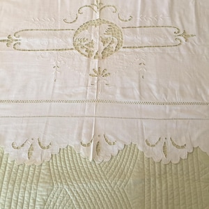 May include: White cotton tablecloth with delicate embroidered floral and bird designs. The tablecloth has a scalloped edge and a center design with a bird in a circle.