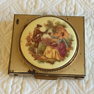 boîte à pilules vintage de style compact. Photo romantique sur boîte à pilules dorée. Six sections pour pilule et miroir à l'intérieur. Occasion.