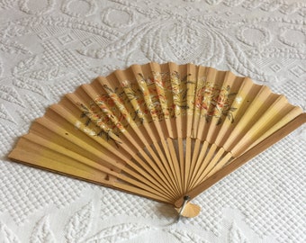 Puede incluir: Un abanico de mano amarillo con un diseño floral. El abanico está hecho de papel y bambú.