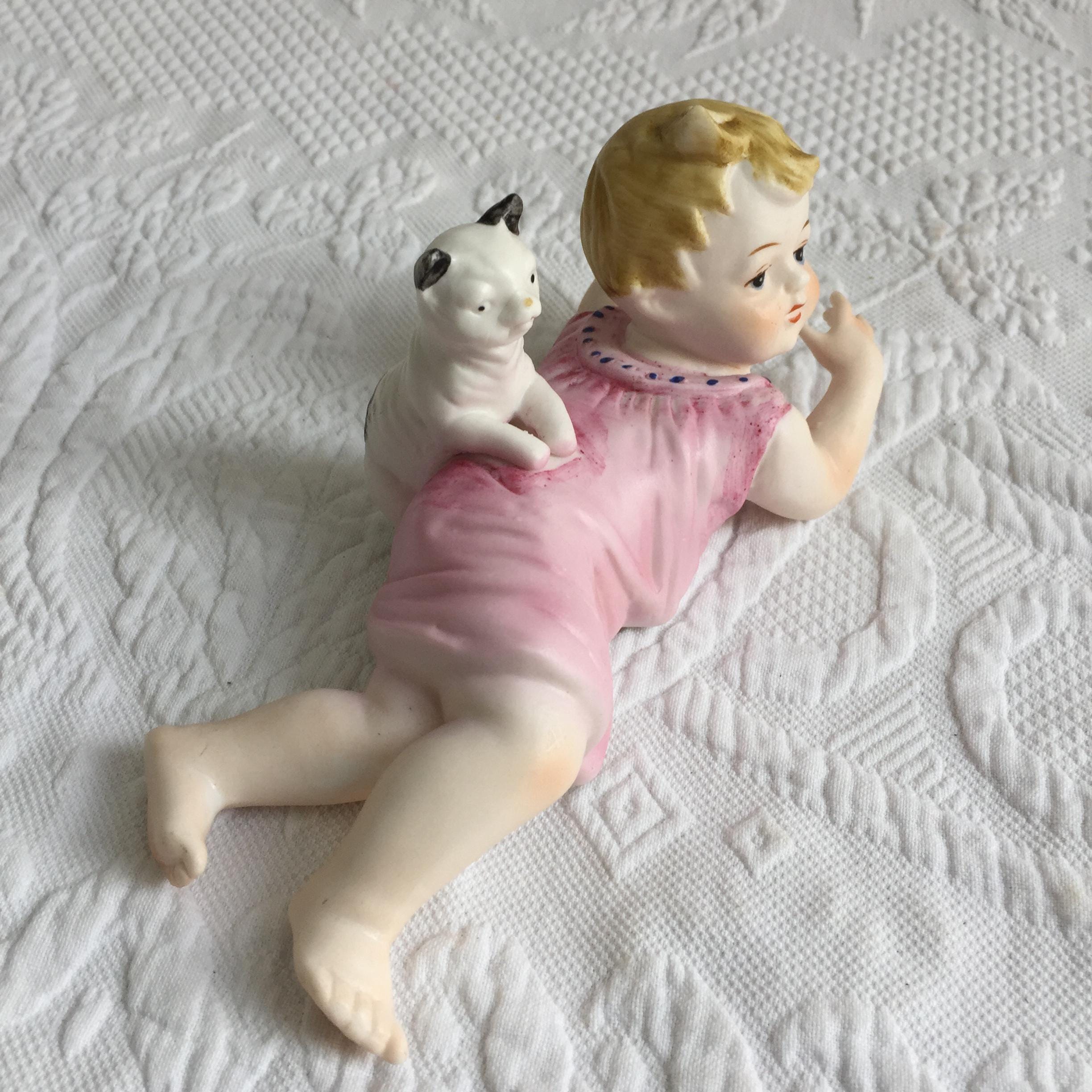 ヴィンテージ磁器の赤ちゃんと猫。赤ちゃんがうつ伏せになり、猫が