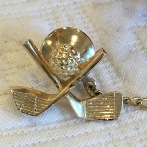 Vintage Tie Pin for Golf Lover. Gold Tone Two Golf Clubs and Golf Ball on Pin. Attached Chain and Cross Bar on Pin Backing.