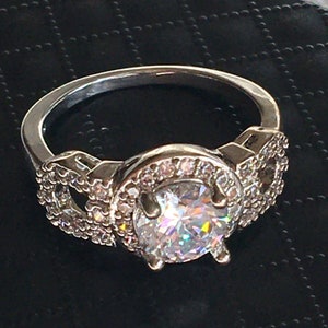Anillo de plata de ley vintage. Marcado S925. Gran diamante redondo incoloro brillante falso. Rodeado de piedras de pavimento y en banda. Talla 9.