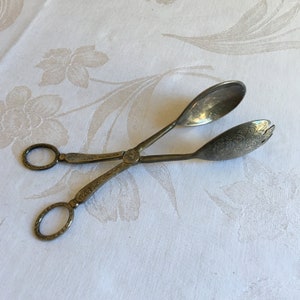 Puede incluir: Tenedores de ensalada de plata con un diseño adornado. Los tenedores tienen dos cucharas en los extremos.