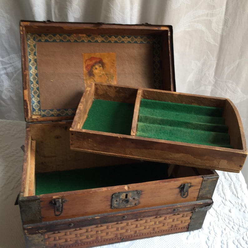 Puede incluir: Un cofre de madera vintage con un forro de fieltro verde y un peque&ntilde;o compartimento con divisores. El cofre tiene un patr&oacute;n tejido en la parte inferior y un cierre de metal.