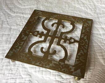 Vintage geëtst messing opengewerkte Aziatisch design onderzetter met vier poten. Gebruik als kookplaat op het aanrecht of op tafel. Oosterse stijl.