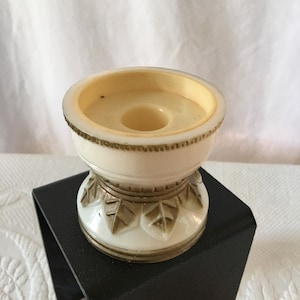Peut inclure: Bougeoir en céramique blanche avec des accents de feuilles d'or. Le bougeoir a une base ronde avec un bord surélevé et une ouverture centrale pour une bougie.