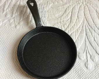 Mała patelnia żeliwna, idealna do użytku lub ekspozycji. Użyj jej do pieczenia dużych ciasteczek lub do powieszenia na ścianie w kuchni.