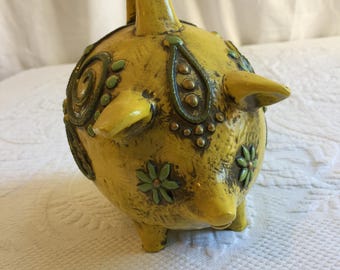 1960年代のヴィンテージ、黄色い豚の貯金箱。黄色い枠に渦巻く緑の模様