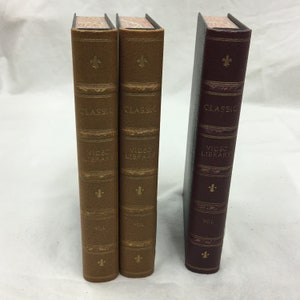 May include: Three leather-bound books with gold lettering. The books are titled "Classic Video Library" and are labeled "Vol." The books are brown and burgundy.