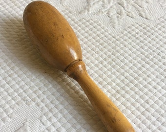 May include: A wooden mallet with a rounded head and a long handle. The mallet is made of light brown wood and has a smooth finish.