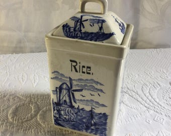 Zabytkowy, niebiesko-biały, ceramiczny lub kamionkowy, kwadratowy pojemnik z Delftu z wiatrakami i żaglówkami. Wyprodukowano w Niemczech.