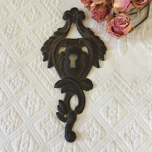Vintage Aged Metal Lock Cover. Decorative Ornament With Key Hole in Center. Swirling Designs on This Lock Cover.