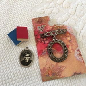 Vintage Mini Oval Frames and Two Mini Books. One Oval Frame is on a Bar Pin. Picture in Silver Metal Oval Frame. Red and Blue Mini Book.