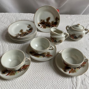 Puede incluir: Un juego de té en miniatura con un diseño de piña. El juego incluye una tetera, una jarra de crema, un azucarero, cuatro tazas de té y cuatro platillos.