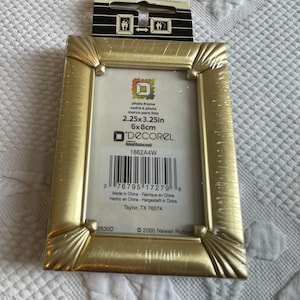 May include: Gold-colored picture frame with a decorative design. The frame is 2.25 inches by 3.25 inches and fits a 6x8 cm photo. The frame is made in China.