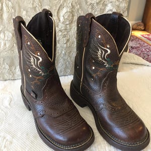 Justin zigeunerlaarzen. L9601 bruine laarzen. Phoenix Design cowgirl-laarzen met decoratief stiksel. Wit koord en zilveren zoolspijkerdetails.