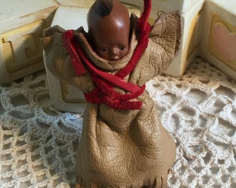 Vintage Mini Baby Papoose American Indian Baby Doll Pin. Wearing Fringed Leather. Baby's Hands Are Holding the Back of His Head.