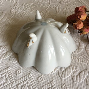 May include: White porcelain bowl with three gold-trimmed feet. The bowl has a scalloped edge and is marked "Made in Japan" on the bottom.