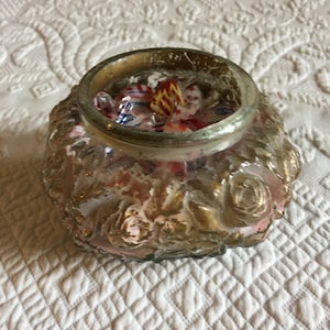 May include: A clear glass jar with a gold and pink floral design, filled with colorful candies.