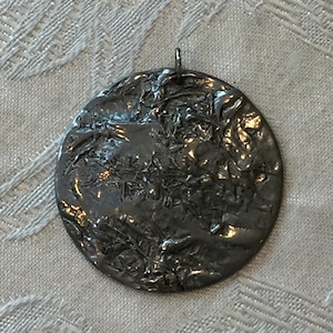 Vintage Gehämmerter Zinn Anhänger. Sieht aus wie geschmolzener Zinnkot in interessanter Konfiguration. Runder Anhänger aus Pewter (Hartzinn).
