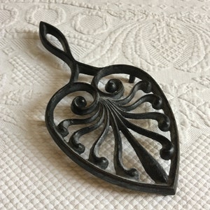 Vintage Cast Iron Trivet with Swirling Designs and Three Feet. Openwork Handle on Top to Hang. Great Kitchen Decoration or Dining Usage.