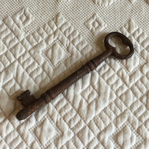 May include: A rusty metal key with a large, rounded head and a long, thin shaft.