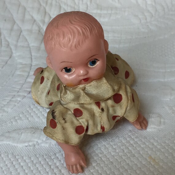 ヴィンテージのゼンマイ巻き上げ式赤ちゃん人形。白地に赤の水玉模様の 