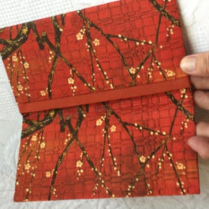 Papel japonés Wagami. Tela no tejida en rojo brillante con espirales amarillos y árbol marrón con blanco y verde. Ideal para recibos, chequeras, etc.