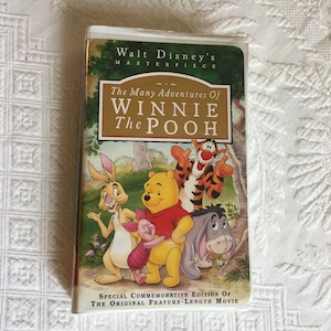 Puede incluir: Casete de video VHS de la obra maestra de Walt Disney, Las muchas aventuras de Winnie the Pooh. La portada presenta a Winnie the Pooh, Tigger, Piglet y Eeyore.