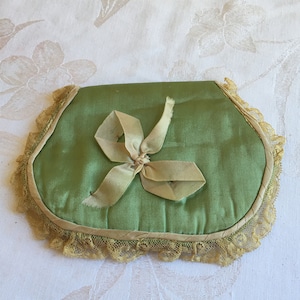 Puede incluir: Una máscara para los ojos de satén verde con un borde de encaje beige y un lazo de satén beige.