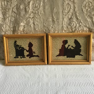 Può includere: Due immagini di silhouette incorniciate. La prima immagine mostra una persona con un cappello in piedi accanto a una stufa. La seconda immagine mostra due persone sedute a un tavolo. Entrambe le immagini hanno una cornice dorata.