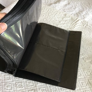 May include: Black photo album with clear plastic sleeves for holding photos. The album is open to reveal the black pages and clear sleeves.