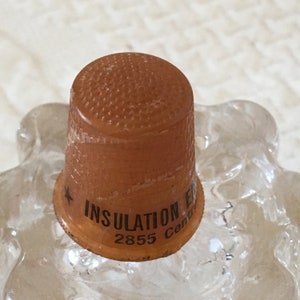 May include: A brown plastic thimble with the text "INSULATION" and "2855" printed on the side.