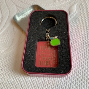 Lehrer-Schlüsselanhänger mit einem grünen Apfel in einer gepolsterten Metallbox. Sagt, Es braucht ein großes Herz, um kleine Köpfe zu formen. Großartiges Geschenk für einen Lehrer.