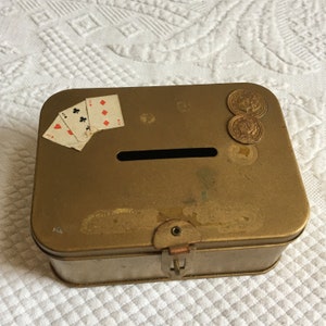 Vintage Gold Metall Box Bank mit Münzen und Spielkarten Designs auf der Oberseite. Riegel auf der Vorderseite hält ein Schloss.